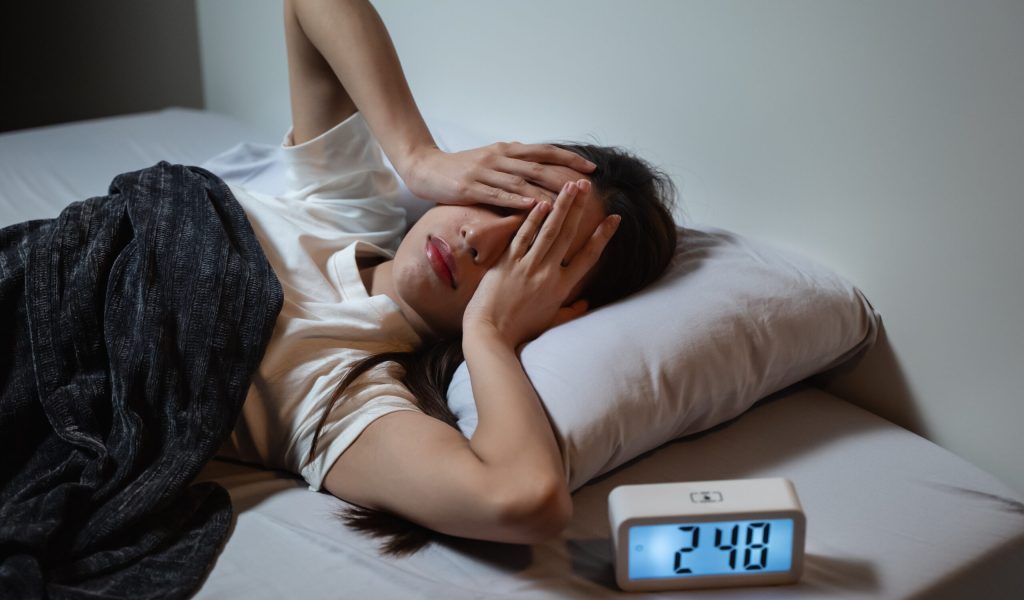 Asian women opened eyes lying on the bed have an insomnia problems.